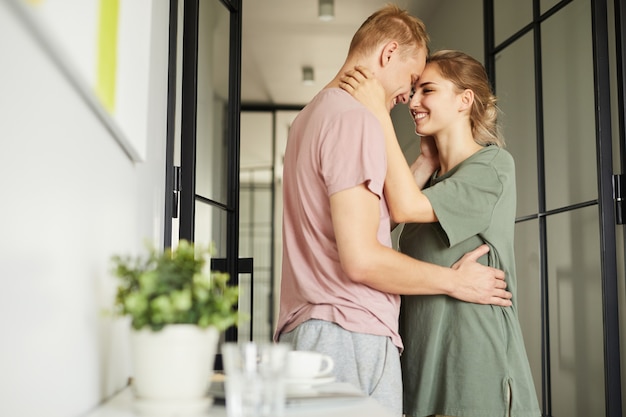 Heureux jeune mari et femme debout dans l'étreinte par la porte