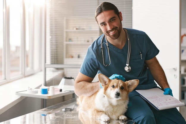 Heureux jeune médecin vétérinaire professionnel avec un chien corgi de race pure