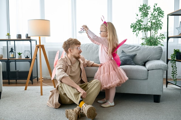 Heureux jeune papa aimant jouer avec une petite fille excitée, activité de jeu amusante à la maison le week-end en famille