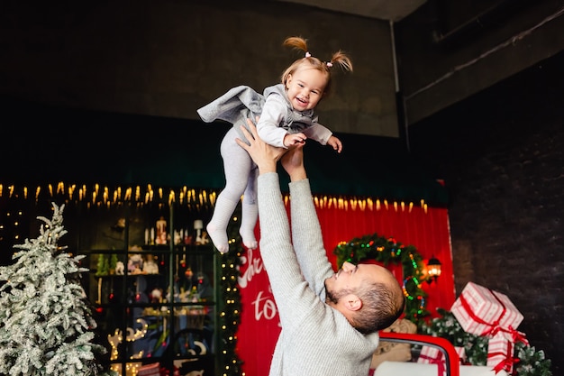 Heureux jeune père caucasien jouant avec sa petite fille sur fond de Noël. Famille. Amusant. Vacances d'hiver du nouvel an.