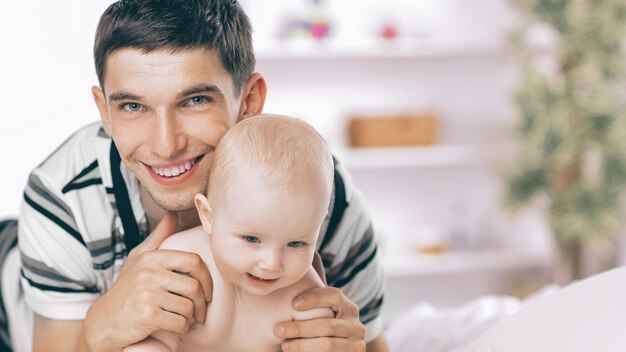 Heureux jeune père jouant avec bébé sur canapé à la maison