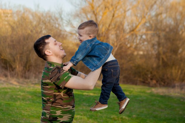 Heureux jeune père jouant avec son fils à l'extérieur