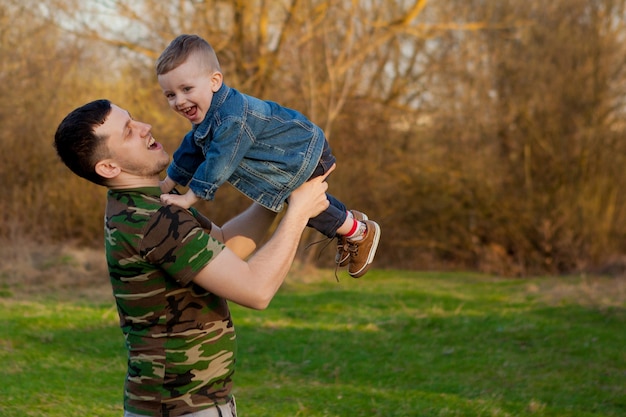 Heureux jeune père jouant avec son fils à l'extérieur.