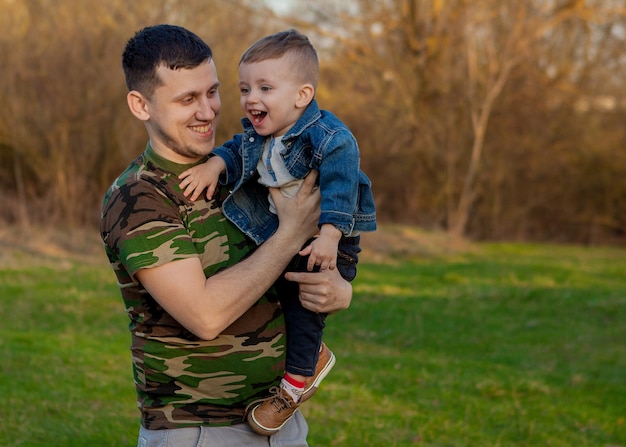 Heureux jeune père jouant avec son fils à l'extérieur.