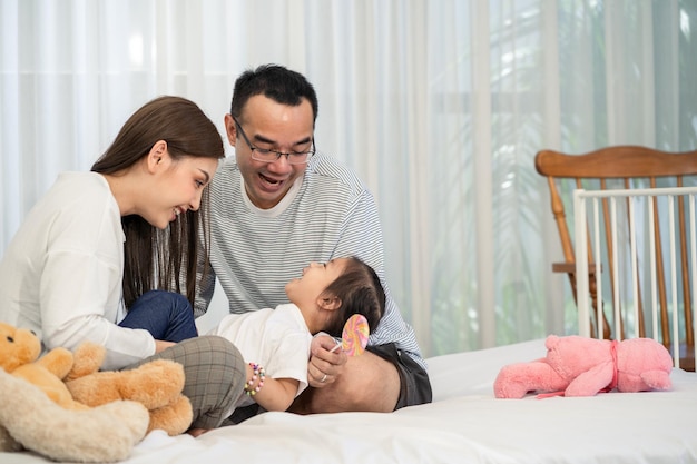 Heureux jeune père et mère et une petite fille jouant avec Toy assis sur le sol dans le salon famille parentalité et concept de personnes