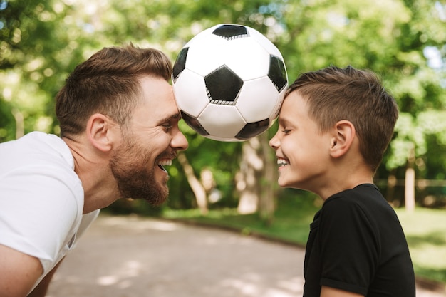 Heureux jeune père s'amuser avec son petit fils avec le football