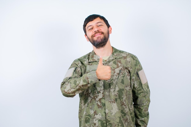 Heureux jeune soldat montre comme un geste avec le pouce sur fond blanc