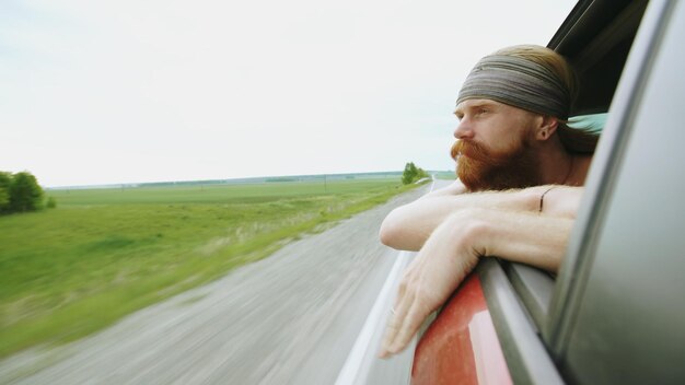 Heureux jeune touriste regardant dans la fenêtre de la voiture détendu en voyageant