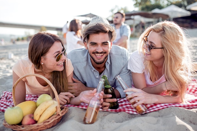 Heureux jeunes amis buvant de la bière sur la plage