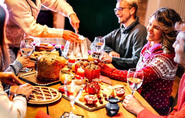 Heureux jeunes amis dégustant des aliments sucrés de Noël s'amusant à la maison du souper