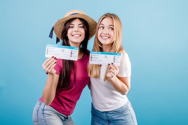 Heureux jeunes femmes souriantes avec des billets d'avion sur bleu