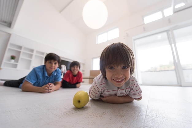 heureux jeunes garçons s'amusant avec une pomme sur le sol dans une nouvelle maison moderne