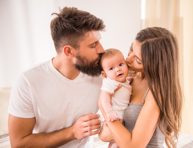 Heureux jeunes parents avec bébé dans le lit à la maison.