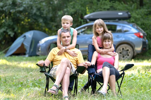 Heureux Jeunes Parents Et Leurs Enfants Se Reposant Ensemble Au Camping En été.