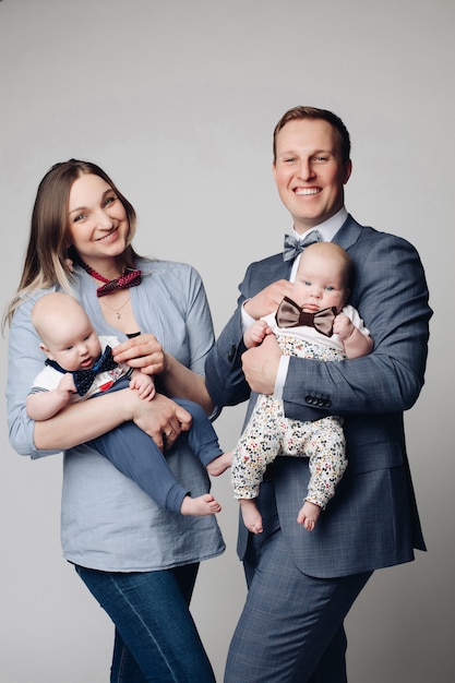 Heureux jeunes parents avec leurs jumeaux souriant à la caméra.