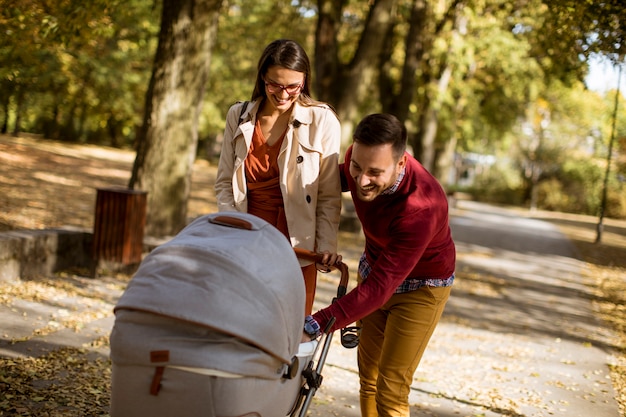 Heureux jeunes parents se promener dans le parc et conduire un bébé en landau