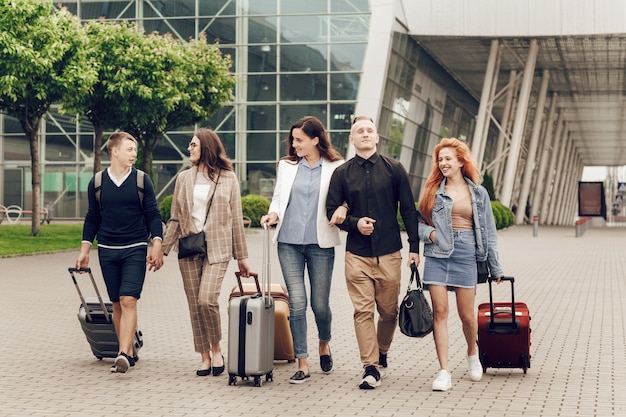 Heureux jeunes positifs avec des bagages en plein air près de l'aéroport.