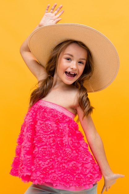 heureux joyeux charmant belle jeune fille avec un chapeau de paille sur la tête sur un mur orange