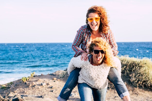 Heureux et joyeux couple de femmes caucasiennes d'âge moyen s'amusent et jouent ensemble en se portant et en riant beaucoup