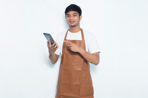 Heureux joyeux jeune barman asiatique barman ou serveuse utilisant un smartphone mobile isolé sur blanc