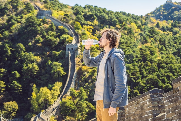 Heureux joyeux touriste joyeux à la grande muraille de chine buvant de l'eau en voyage de vacances en asie