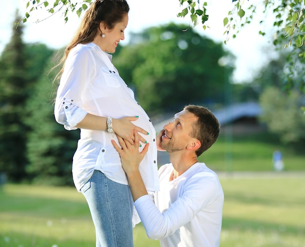 Heureux mari embrassant sa femme enceinte lors d'une promenade dans le parc