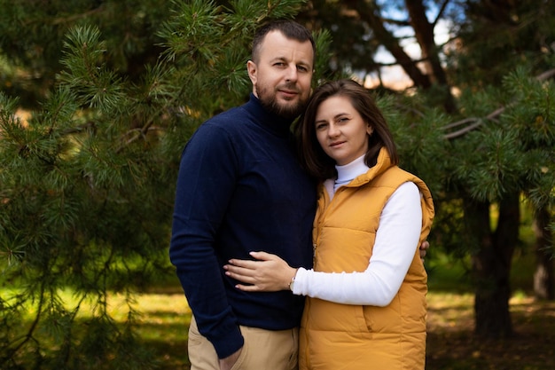 Photo heureux mari et femme adultes dans le stand de la forêt d'automne embrassant