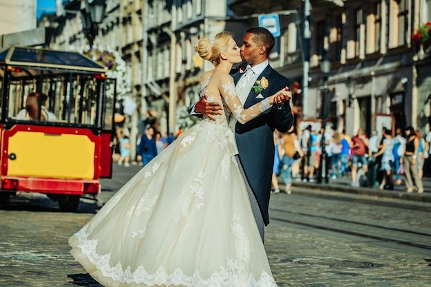 Heureux marié afro-américain et jolie mariée dansant dans la rue