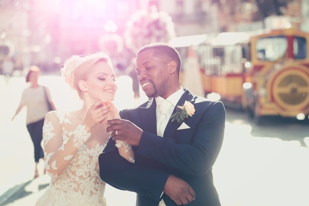 Heureux marié afro-américain et jolie mariée marchant dans la rue