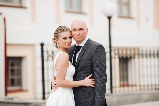 Heureux marié fort caucasien en costume gris aime sa jolie jeune mariée