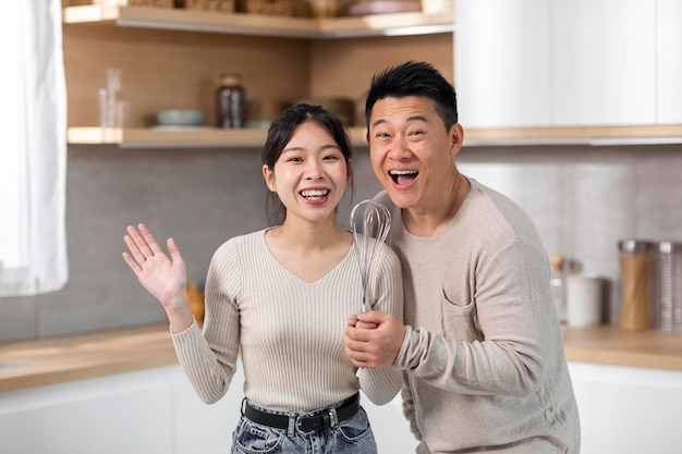 Heureux mariés asiatiques chantant à la cuisine