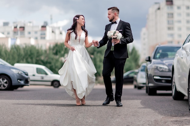 Heureux mariés marchant dans la rue de la grande ville. vacances et événements