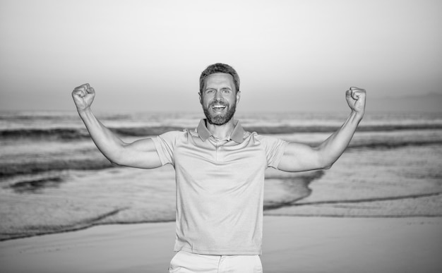 Heureux mec au-dessus de la mer sur les émotions de la plage d'été au lever du soleil