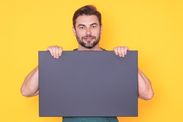 Heureux mec avec une bannière vierge isolée sur fond de studio portrait of smiling man holding b vide