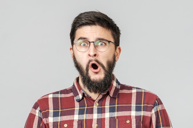 Heureux mec excité dans des verres isolés sur gris