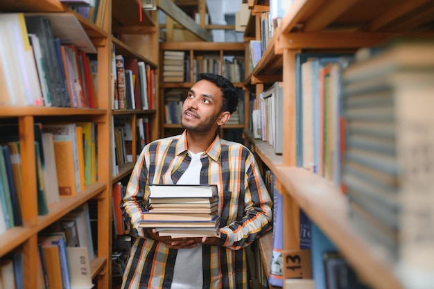 Heureux mec indien ou arabe intelligent étudiant universitaire masculin de race mixte dans la bibliothèque