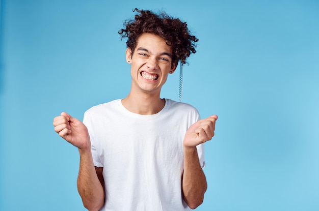 Heureux mec avec un peigne à la main sur un fond bleu et modèle brune cheveux bouclés