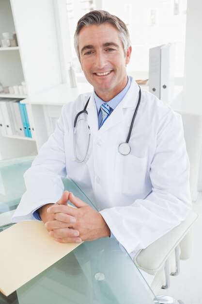 Photo heureux médecin assis à son bureau