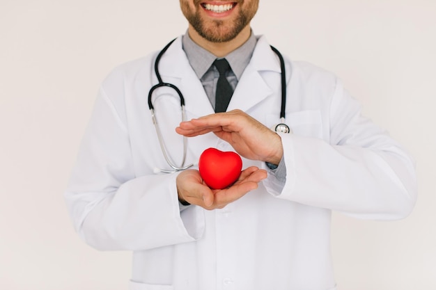 L'heureux médecin cardiologue masculin tenant le coeur sur fond blanc