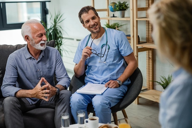 Heureux médecin généraliste communiquant avec des patients âgés lors d'une visite à domicile