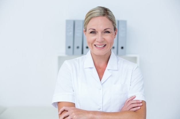 Heureux médecin regardant la caméra avec les bras croisés