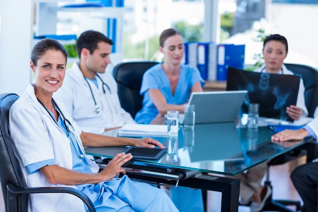 Heureux médecin regardant la caméra avec des collègues derrière