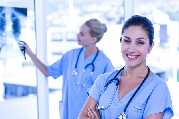 Heureux médecin regardant la caméra pendant que ses collègues regardent Xray