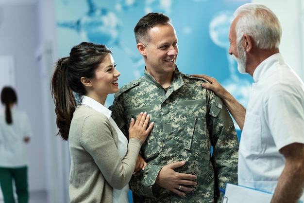 Heureux médecin senior communiquant avec un militaire et sa femme après le rendez-vous à l'hôpital