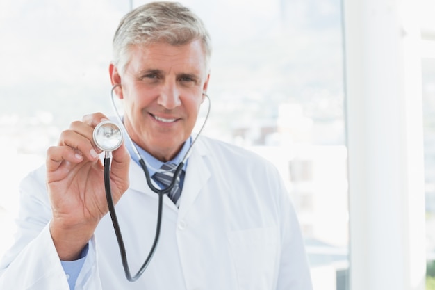 Heureux médecin souriant à la caméra et montrant son stéthoscope