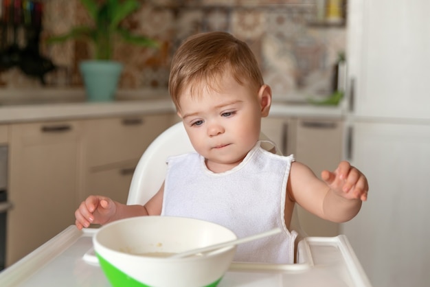 Heureux mignon bébé garçon se mange. Petit garçon caucasien avec grimace concentré sur la nourriture. Essayez de manger tout seul. Alimentation de l'enfant.