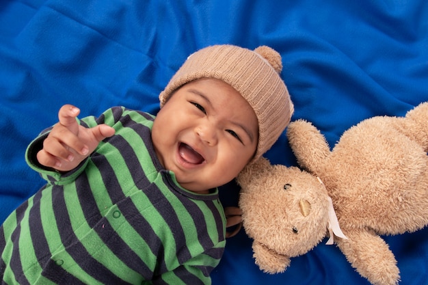 Photo heureux mignon petit bébé garçon couché sur une couverture bleue et souriant