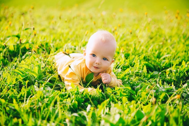 Heureux mignon petit enfant souriant allongé sur l'herbe verte du pré en été. Famille sur la nature.