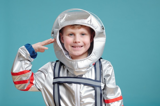 Heureux mignon petit garçon en combinaison spatiale gardant la main par temple