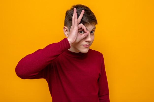 Heureux de montrer un geste de regard jeune beau mec portant un pull rouge isolé sur un mur orange